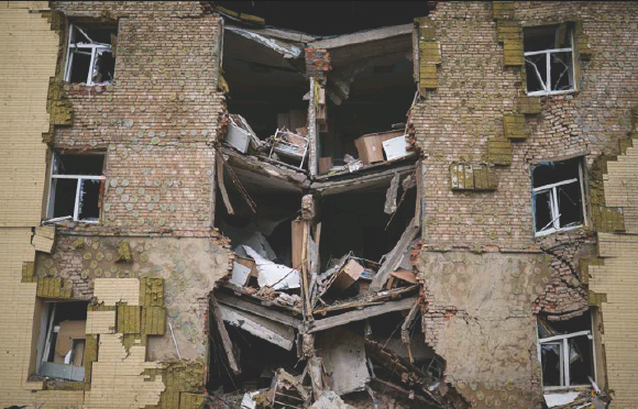 Debris hangs from a res­id­en­tial build­ing heav­ily dam­aged in a Rus­sian bomb­ing in Bakh­mut, east­ern Ukraine, east­ern Ukraine, in May.