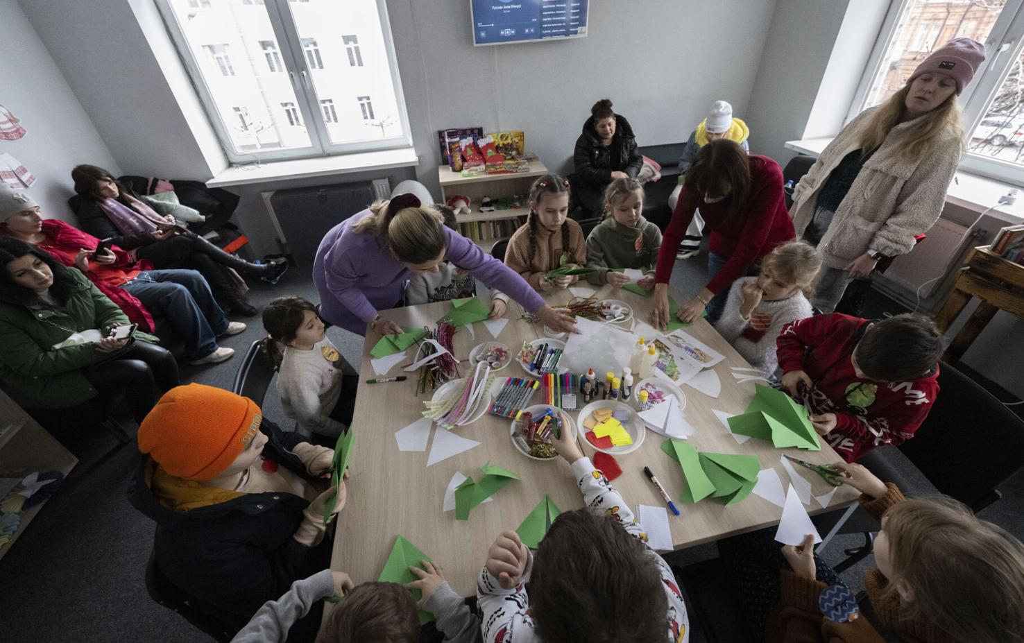 Counselors Diana Veadykina, in purple, and Maryna Starovoitova help refugee children with their Christmas crafts Dec. 11, 2023, at a government hub in Dnipro, Ukraine.