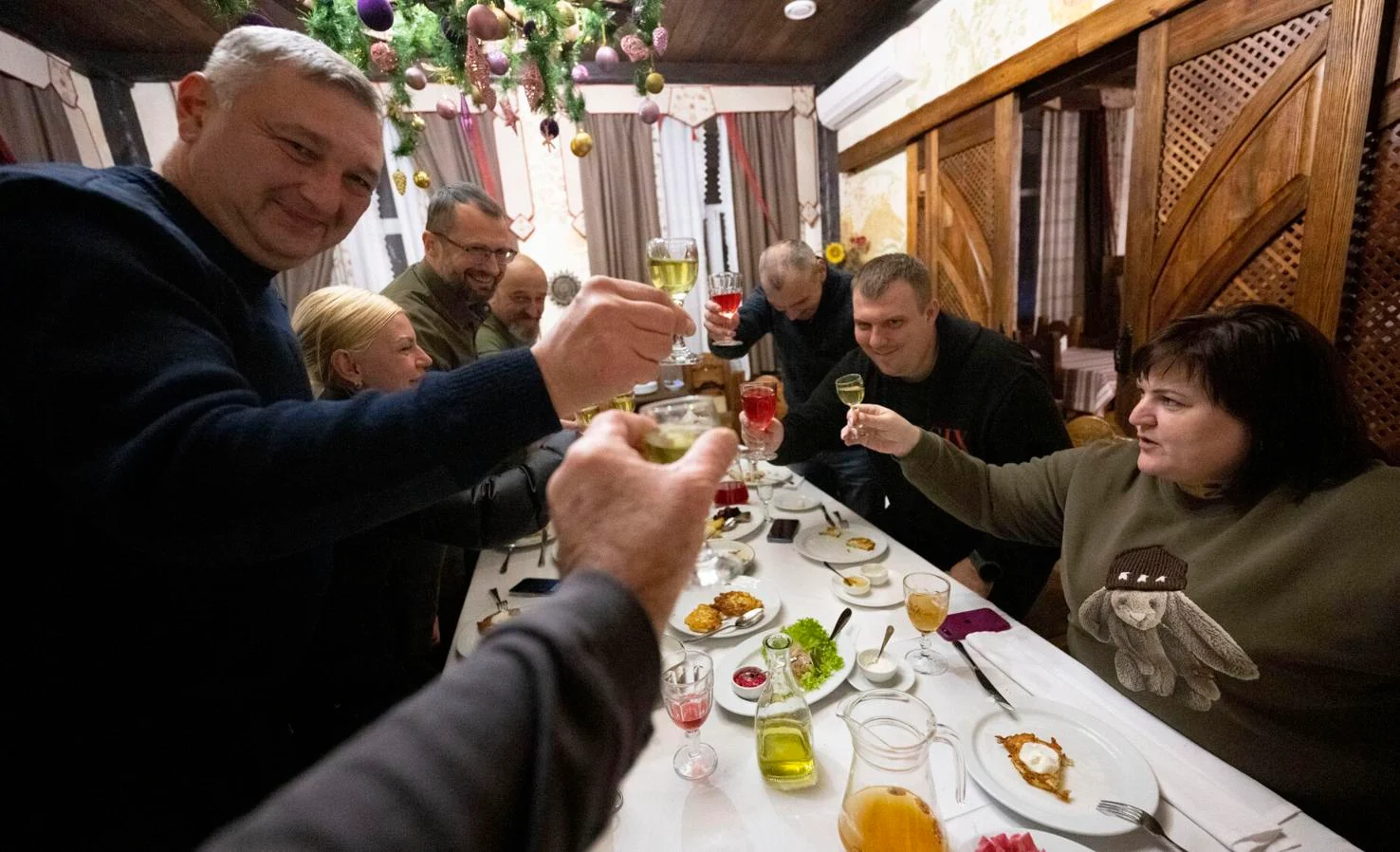 Yana Malyk toasts to good friends including Sergi Polyakov, left, Oleksii Smirnov, first deputy governor of Luhansk military administration, on her left; Oleg Sleptets, governor of Savatovo military administration, back left, and Galyna Radchenko, governor of Kolomiychiha village military administration, on the right, after a day of touring Kharkiv, Ukraine, Dec. 13, 2023.